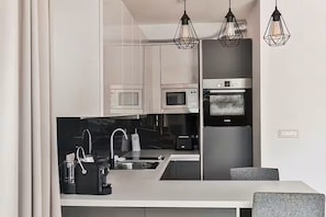 Eine moderne Küche mit integriertem Mikrowellenherd, Backofen und Spüle. Über der Arbeitsfläche befinden sich Pendelleuchten.