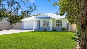 Einbungalow mit Garage, einer überdachten Veranda und einem gepflegten Rasen.