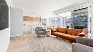 Ein modernes Wohnzimmer mit einem braunen Ledersofa, einem grauen Sessel und einem gemusterten Teppich.