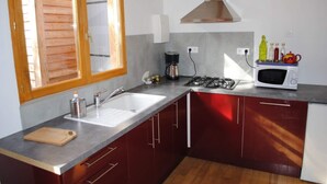 Una cocina con un lavamanos, estufa, microondas y persianas de madera.