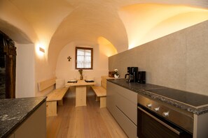 Una cucina con una panca di legno, una macchina per il caffè e una finestra con tende.