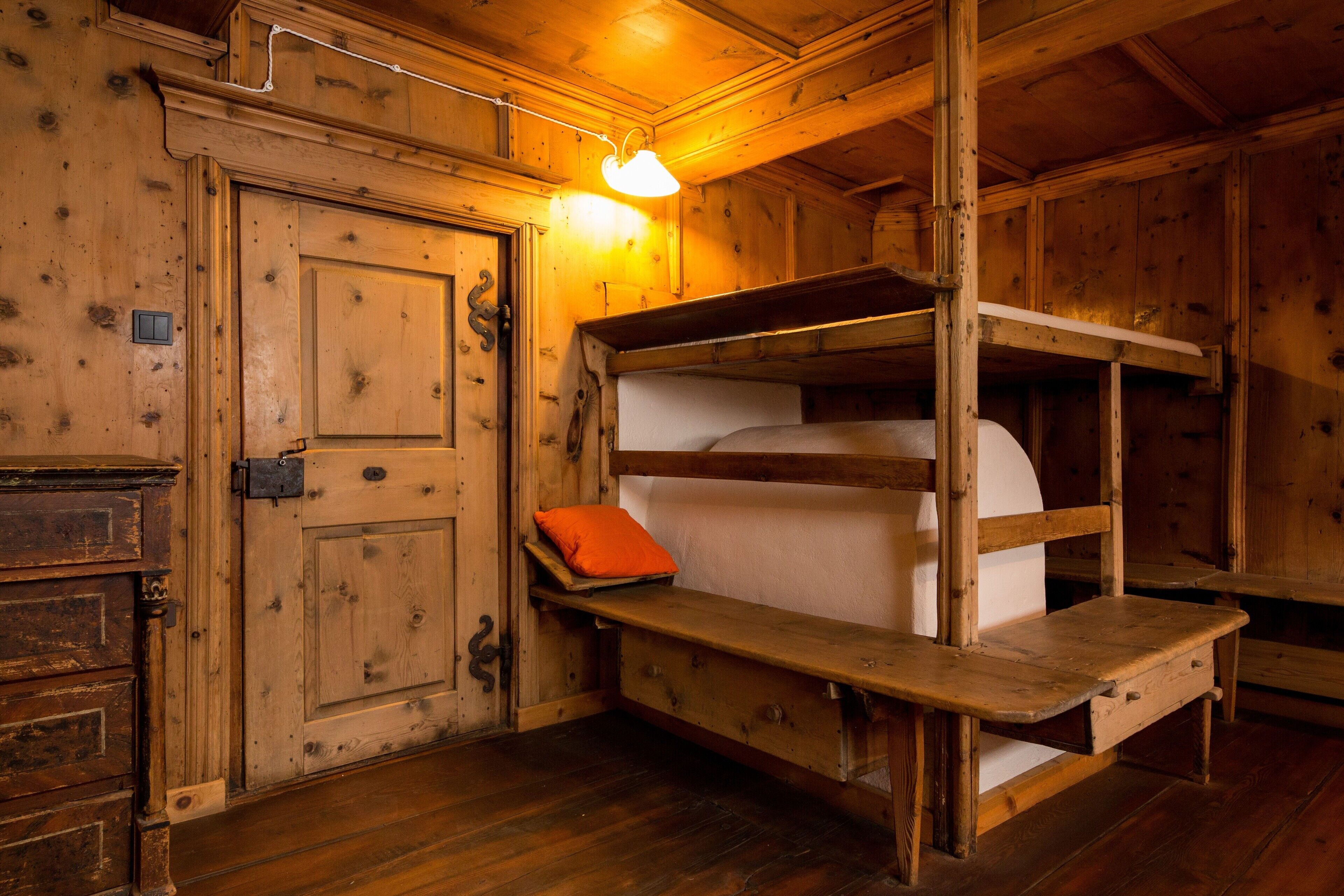 Una habitación de madera con literas, una puerta y un banco.