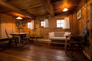 Un interno in legno con un tavolo da pranzo, sedie, un divano e una panca.