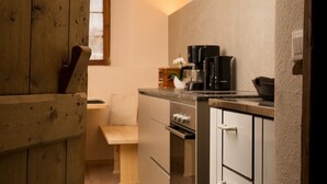 Una cuina amb armaris de fusta, una taulell i una màquina de cafè.