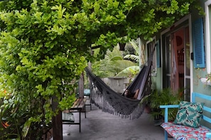 A hammock under a tree, a wooden bench, and a blue bench with a patterned cushion. - Praia do Sagi (Baía Formosa)