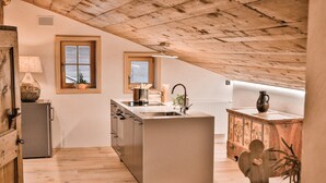 Una cocina con vigas de madera, un refrigerador, un lavabo y una ventana.