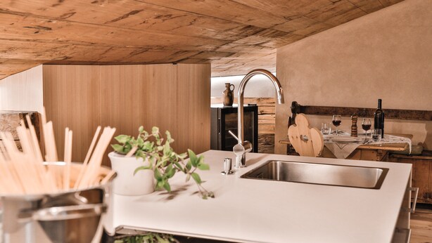 Una cocina moderna con techo de madera, encimera blanca y pileta.
