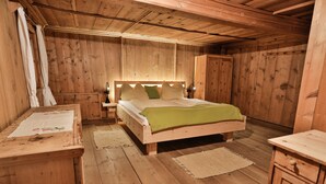 Un dormitorio de cabaña de madera con cama, mesitas de noche y cómoda.