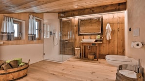 Un baño de cabaña de madera con box de ducha de vidrio, un lavamanos y un inodoro.