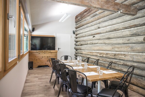 Une salle de conférence avec une table et des chaises en bois, un tableau blanc et un mur en rondins.