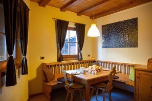 Un coin repas chaleureux avec une table en bois, des bancs et un luminaire suspendu.