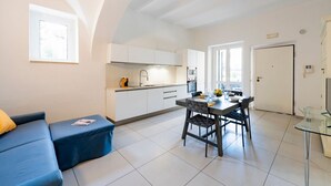 A modern kitchen with white cabinets, a dining table with chairs, and a glass coffee table. - GuestHost - A comfortable and welcoming 64 square meters apartment, perfect for four people, located on the ground floor of a renovated period villa with a private entrance.The property is located in Alba Adriatica, a town famous for its long sandy beach (Alba Adriatica)