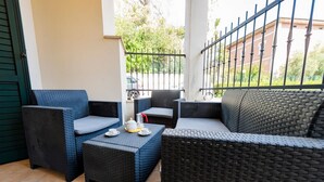 A balcony with wicker furniture, a table with a teapot, and a view of a street and greenery. - GuestHost - A comfortable and welcoming 64 square meters apartment, perfect for four people, located on the ground floor of a renovated period villa with a private entrance.The property is located in Alba Adriatica, a town famous for its long sandy beach (Alba Adriatica)