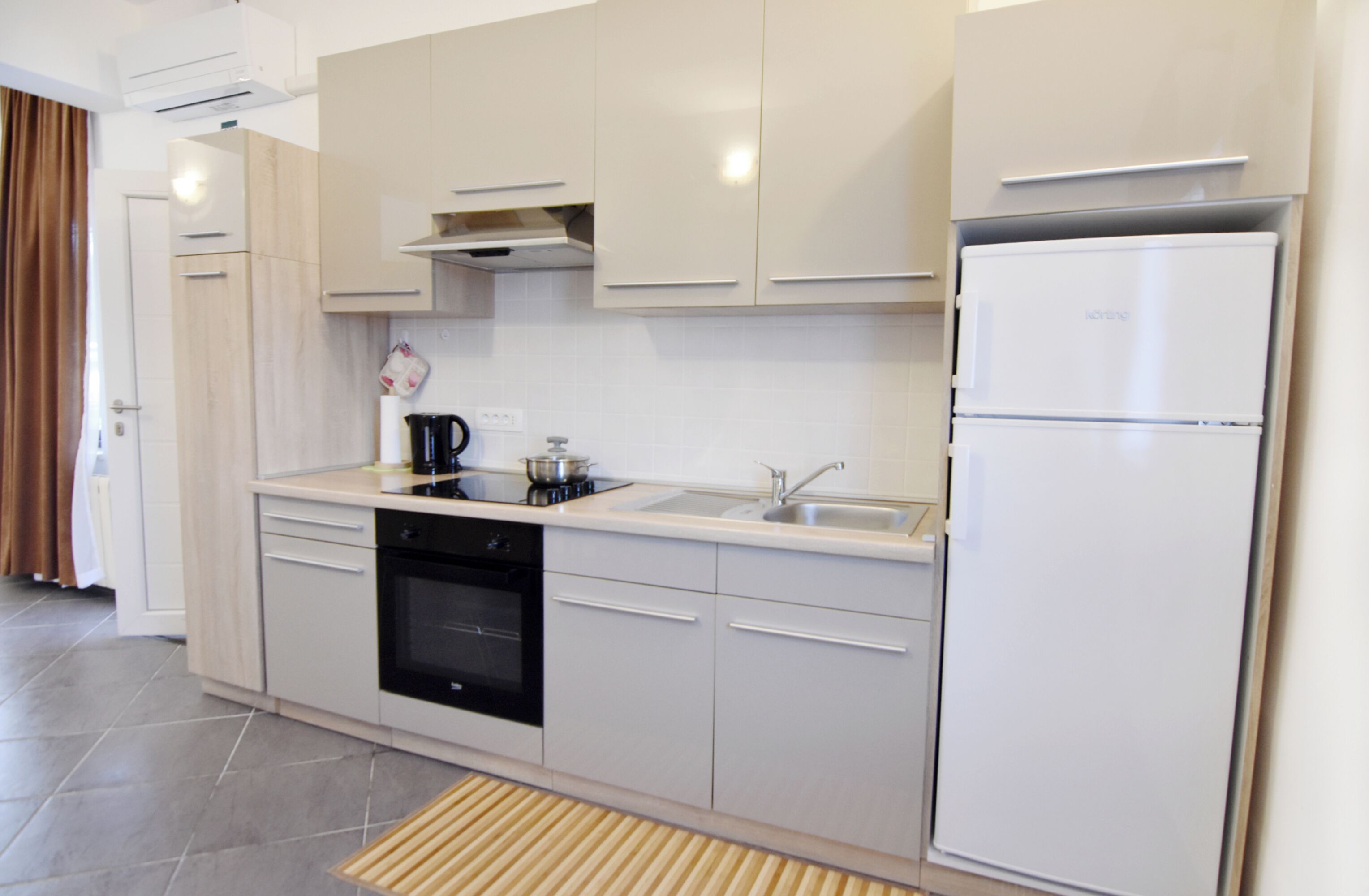 A modern kitchen with a built-in oven, a sink, and a refrigerator.