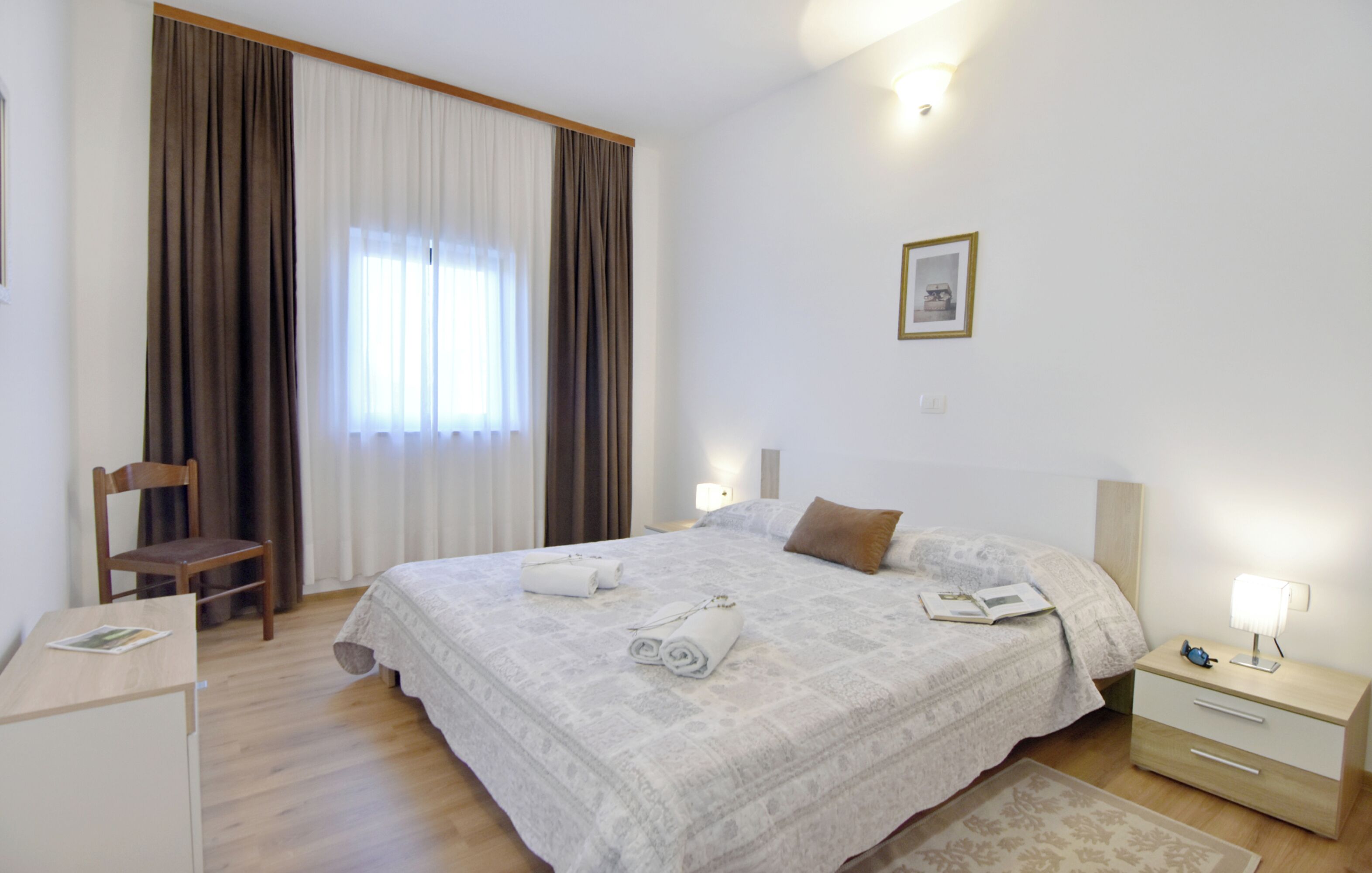 Une chambre à coucher comprenant un lit, une table de chevet, une chaise et un bureau.