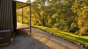 Un'area relax all'aperto con tettoia, un sentiero in ghiaia e una panca di legno.