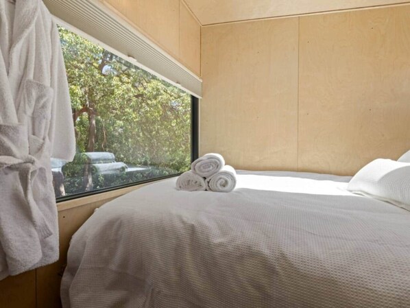 A bedroom with a bed, a window, and a view of trees.