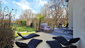Een terras met lounge fauteuils, een bank en een hangstoel.