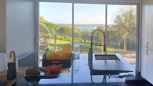 Een moderne keuken met een groot raam, een spoelbak en een eethoek met een tafel en stoelen.