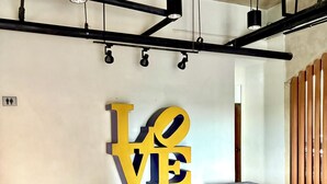 A modern interior with a large 'LOVE' sign, two grey sofas, wooden flooring, and a ceiling with exposed beams and lighting fixtures. - Elle’s Haven: A Chic & Cozy Staycation in the Heart of Cebu (Cebu City)