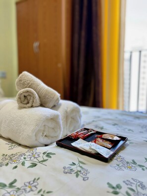 Un lit bien fait, avec des serviettes pliées et une tablette contenant des articles de toilette.