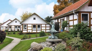 A row of traditional half-timbered houses with a stone fountain in the garden. - Feriendorf an der Ostsee, Wohlenberg (Wohlenberg)