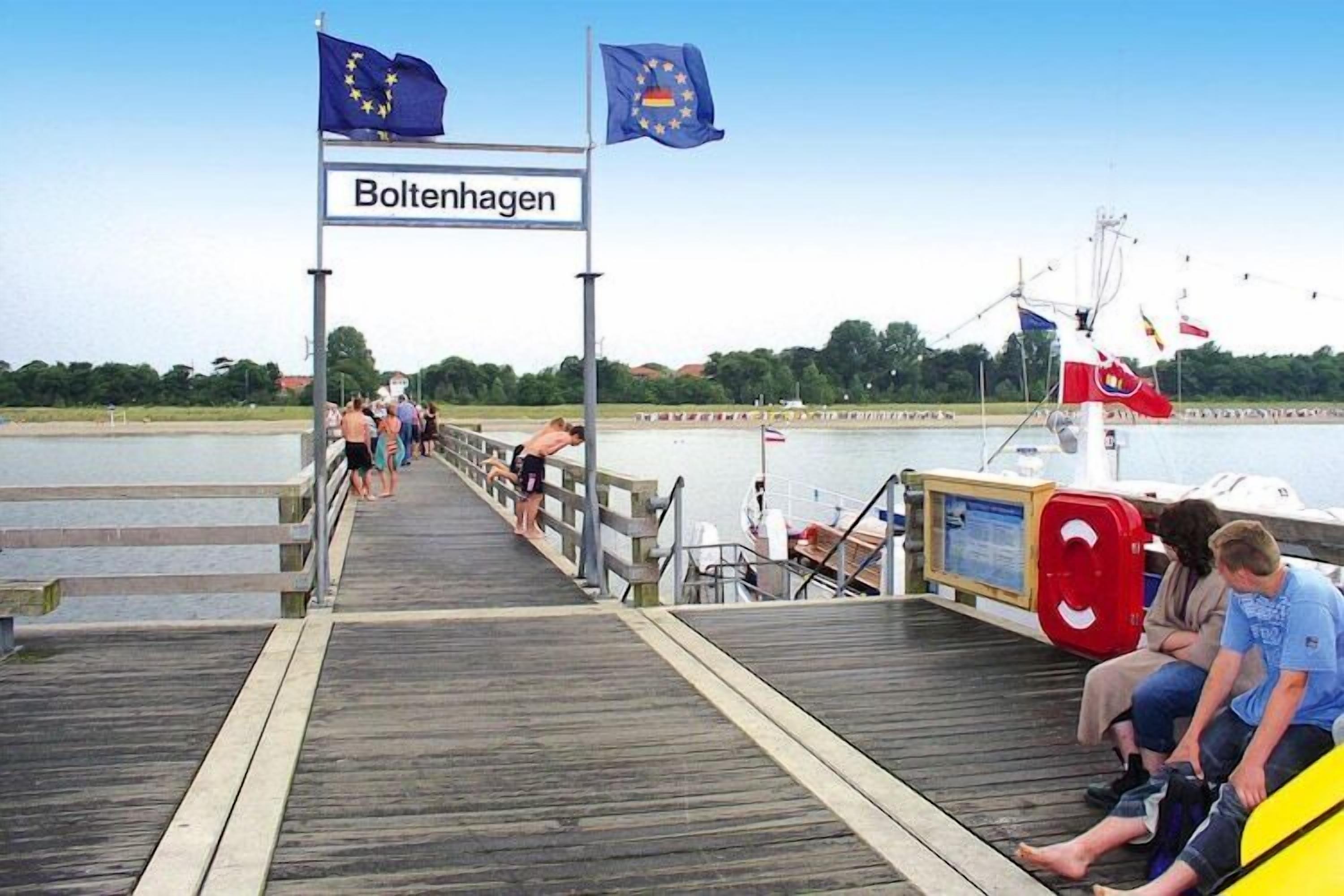A wooden pier with a sign reading 'Boltenhagen' and flags of the European Union and Germany.