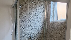 Une salle de bain avec douche, toilettes et lavabo.