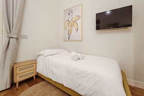 Ein Schlafzimmer mit Bett, Fernseher, Wandbild und Nachttisch.