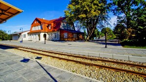 Une gare avec un bâtiment à toit rouge, des voies ferrées et un quai.