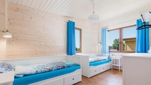 Une chambre avec deux lits, un bureau et une fenêtre avec des rideaux.