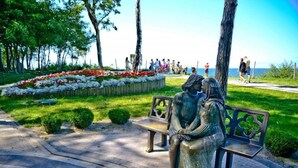 Un parc avec un banc orné d’une sculpture représentant deux personnages.