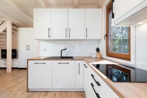 Eine moderne Küche mit weißen Schränken, einem schwarzen Spülbecken und einem Fenster mit Blick auf Bäume.