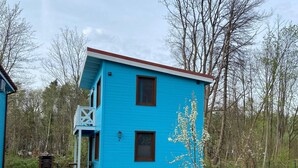 Una casa blu di due piani con un piccolo portico e un camino.