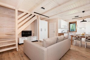 Ein modernes Interieur mit einer Couch, einem Fernseher, einer Treppe und einer Küchenzeile.