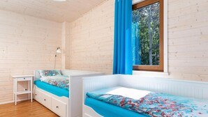 Una habitación con dos literas, un escritorio blanco pequeño, una lámpara y una ventana con cortinas azules.
