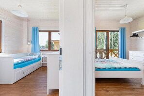 A bedroom with a bed, a desk, and a window.