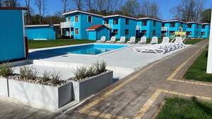 A pool area with lounge chairs and a clear sky.