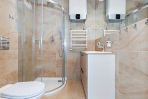 Une salle de bain moderne avec une douche à parois de verre, des toilettes blanches et un lavabo avec un miroir.