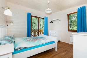 Ein Schlafzimmer mit Bett, Kommode, einem Fenster mit Vorhängen und einem Deckenventilator.
