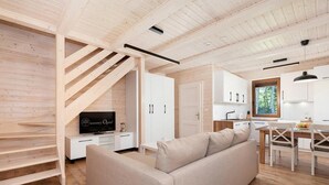 En modern inredning med en trappa i trä, en soffa, en matplats och ett kök.