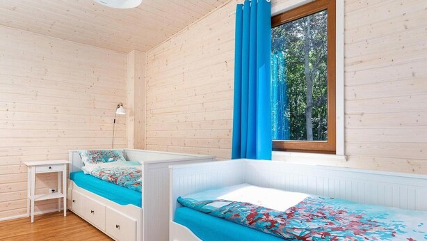 Una habitación con dos literas, una mesita, una lámpara y una ventana con cortinas azules.