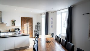 A modern kitchen with a dining area, wooden cabinets, and a large window. - Le grand gîte du domaine d'Embourg (Souvigny)