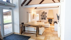 A living room with a white sofa, a wooden coffee table, a fireplace, and a door leading outside. - Le grand gîte du domaine d'Embourg (Souvigny)