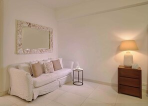 A room with a white sofa, a small round table with a cup, a lamp, and a wooden dresser. - ®{3BR~Hemingway~Retreat}@JuanDolio+Pool (Juan Dolio)