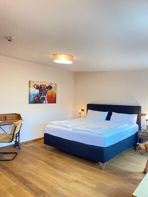 Una camera da letto con un letto, una scrivania e un quadro appeso al muro.