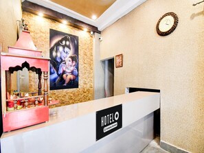 A hotel reception desk with a 'HOTELO' sign, a clock, and a framed picture on the wall. - Deluxefamily Guest House (Gaya)