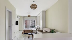A modern living room with a sofa, a coffee table, and a large window. - Verde Premium Apartments (Thessaloniki)