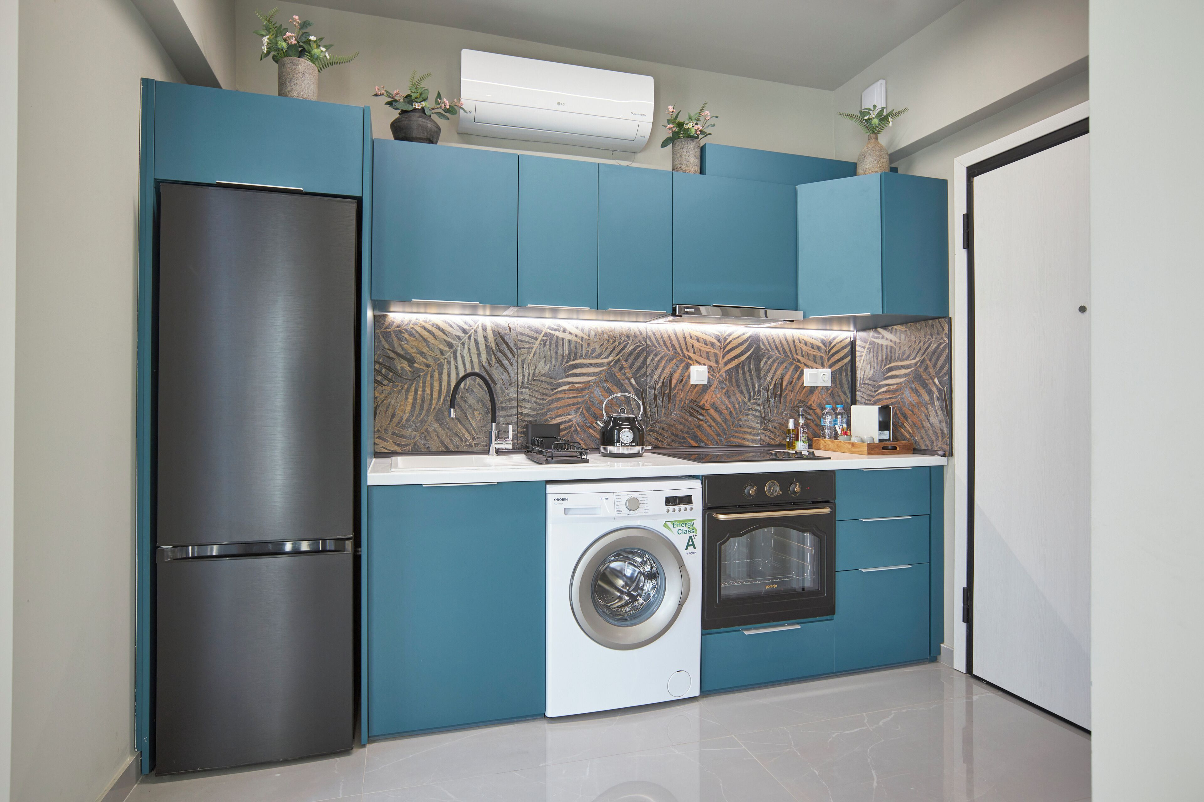 Une cuisine compacte équipée d’un réfrigérateur, d’un lave-linge, d’un four et d’un four à micro-ondes.