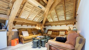 Un espacio tipo loft con vigas de madera a la vista, sofás de cuero y una mesa de centro de vidrio.
